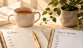 Reflection journal, weekly planner, tea and a growing plant.